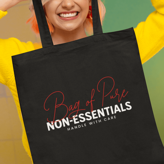 Model holding black eco tote bag featuring “Bag of Pure Non-Essentials Handle with Care” funny typography design by LostLogicCo Canada.