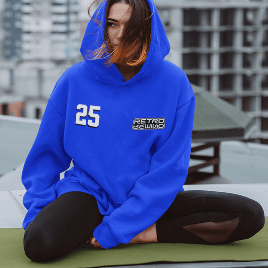 Model wearing blue hoodie featuring bold “25” numeric graphic with retro sewn accent, unisex streetwear by LostLogicCo Canada