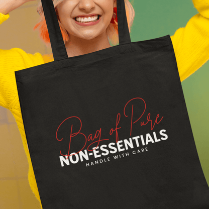 Model holding black eco tote bag featuring “Bag of Pure Non-Essentials Handle with Care” funny typography design by LostLogicCo Canada.