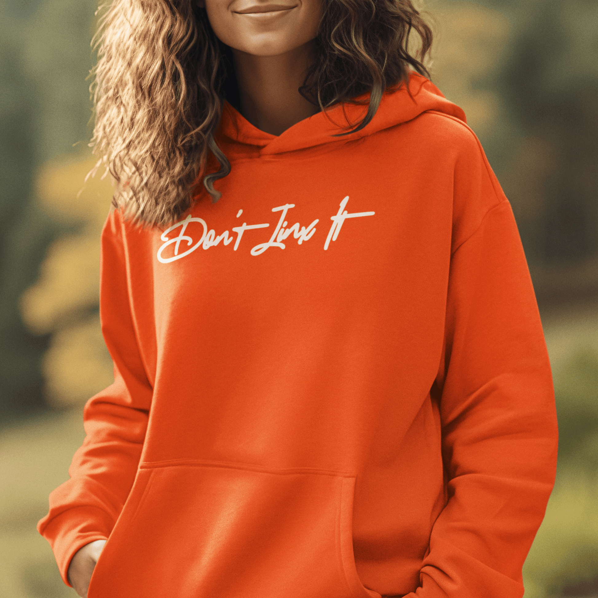 Female Model wearing orange hoodie featuring white handwritten “Don’t Jinx It” script, modern minimal streetwear by LostLogicCo Canada