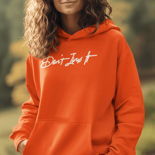 Female Model wearing orange hoodie featuring white handwritten “Don’t Jinx It” script, modern minimal streetwear by LostLogicCo Canada