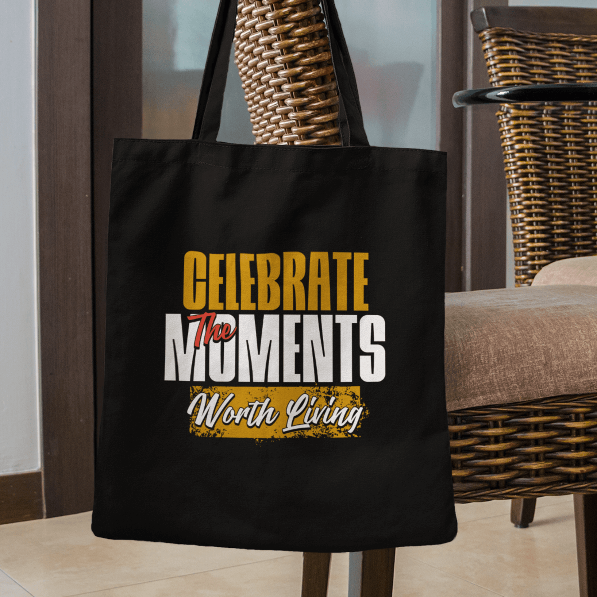 Eco tote bag with “Celebrate the Moments Worth Living” typography design in white, gold, and yellow on black organic cotton by LostLogicCo Canada.