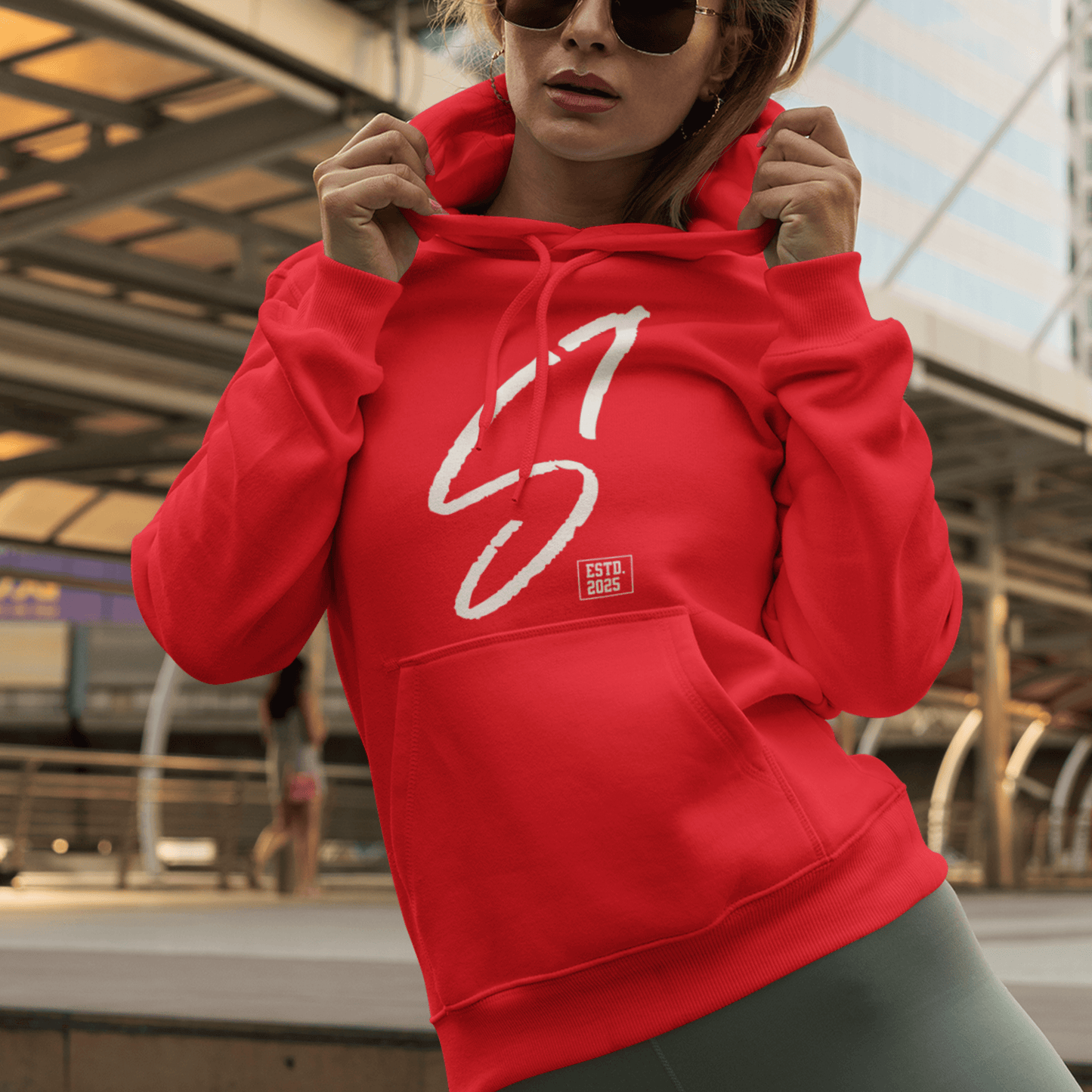 Female Model wearing red hoodie featuring bold minimal “S1” signature graphic, modern streetwear design by LostLogicCo Canada