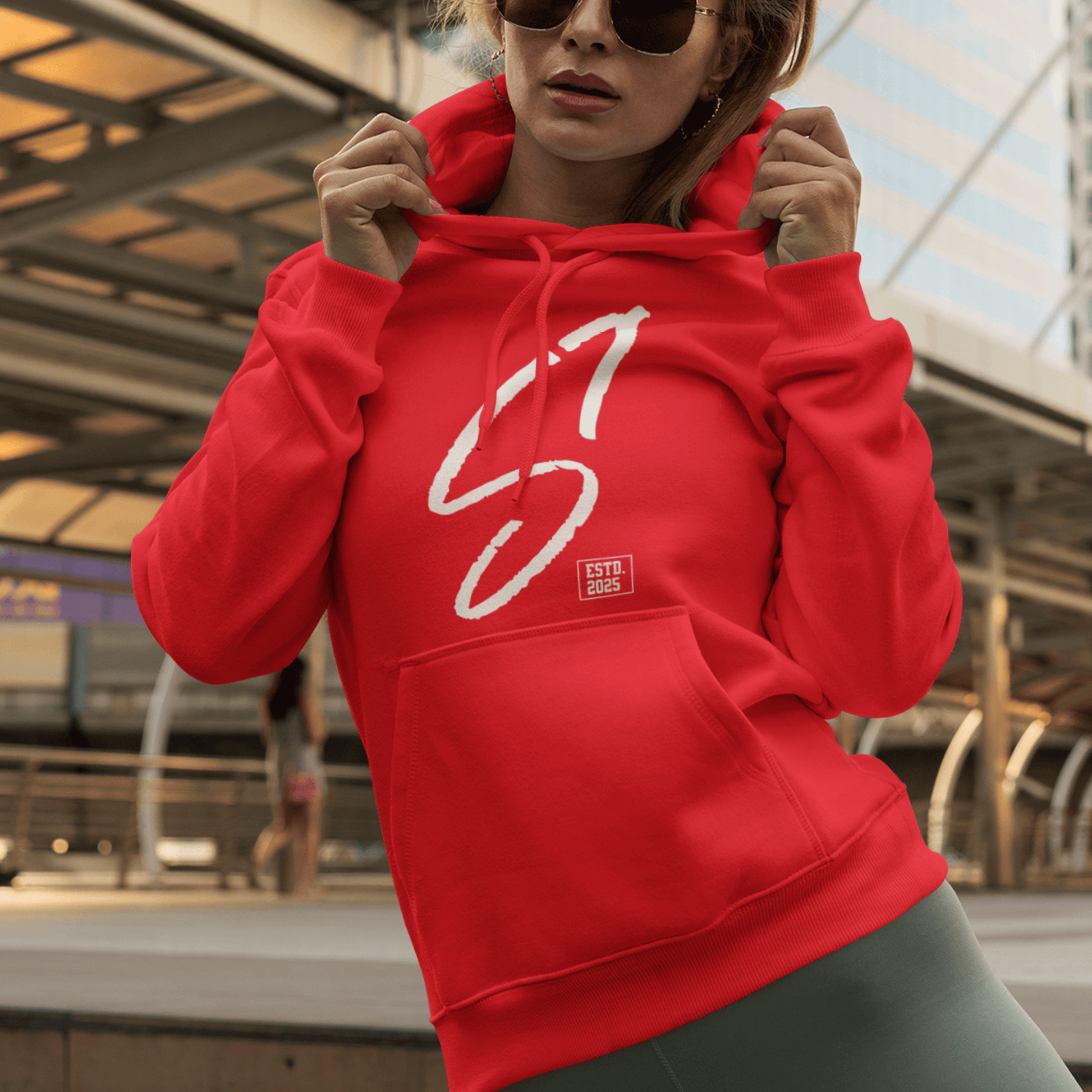 Female Model wearing red hoodie featuring bold minimal “S1” signature graphic, modern streetwear design by LostLogicCo Canada