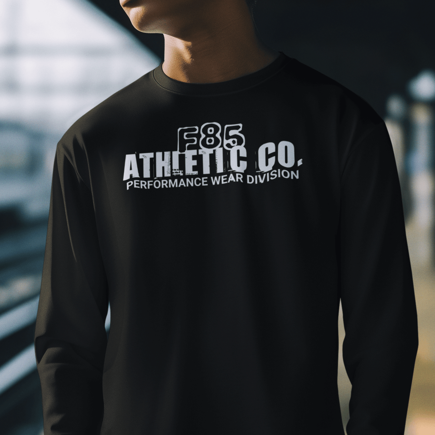 Model wearing “F85 Athletic Co. Performance Wear Division” black unisex sweatshirt with simple white typography design, cozy crewneck by LostLogicCo Canada