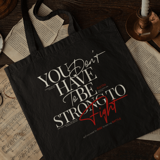 Eco tote bag with “You Don’t Have to Be Strong to Fight” motivational typography design in white and red on black organic cotton by LostLogicCo Canada.