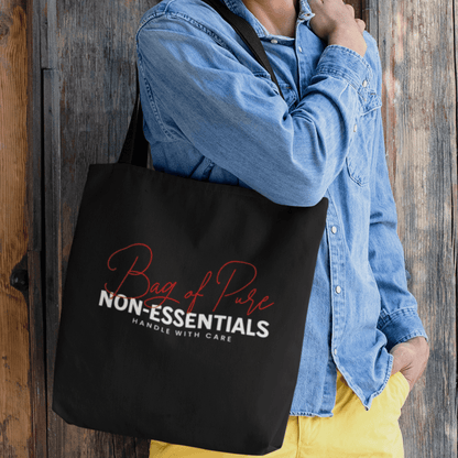 Model holding black eco tote bag featuring “Bag of Pure Non-Essentials Handle with Care” funny typography design by LostLogicCo Canada.
