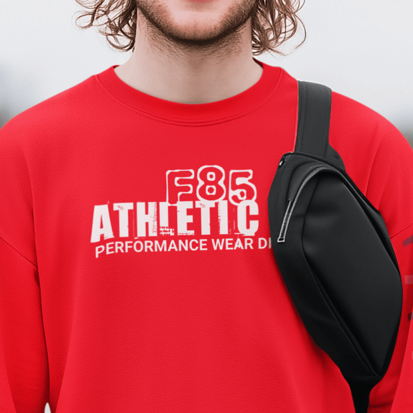 Model wearing “F85 Athletic Co. Performance Wear Division” black unisex sweatshirt with simple white typography design, cozy crewneck by LostLogicCo Canada