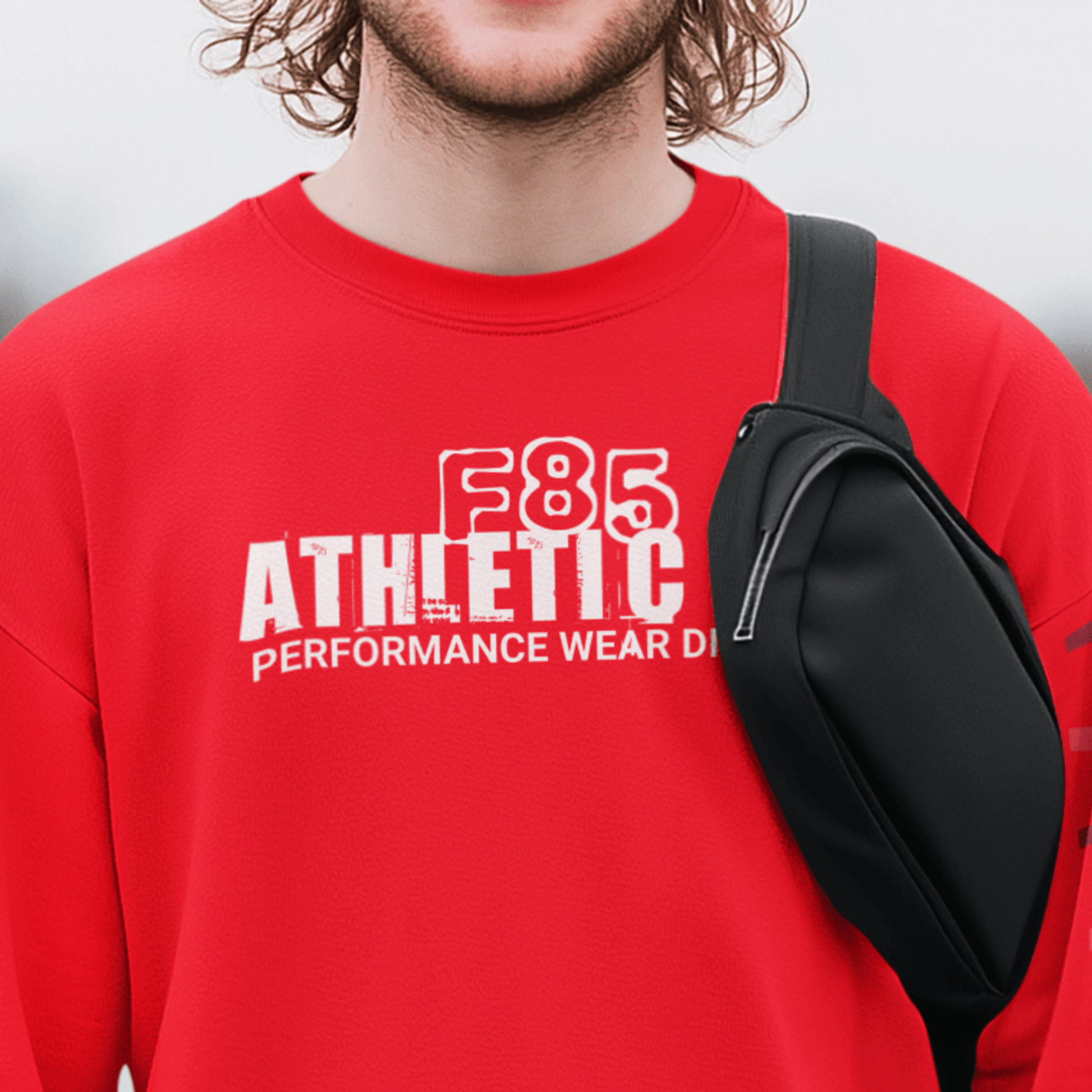 Model wearing “F85 Athletic Co. Performance Wear Division” black unisex sweatshirt with simple white typography design, cozy crewneck by LostLogicCo Canada