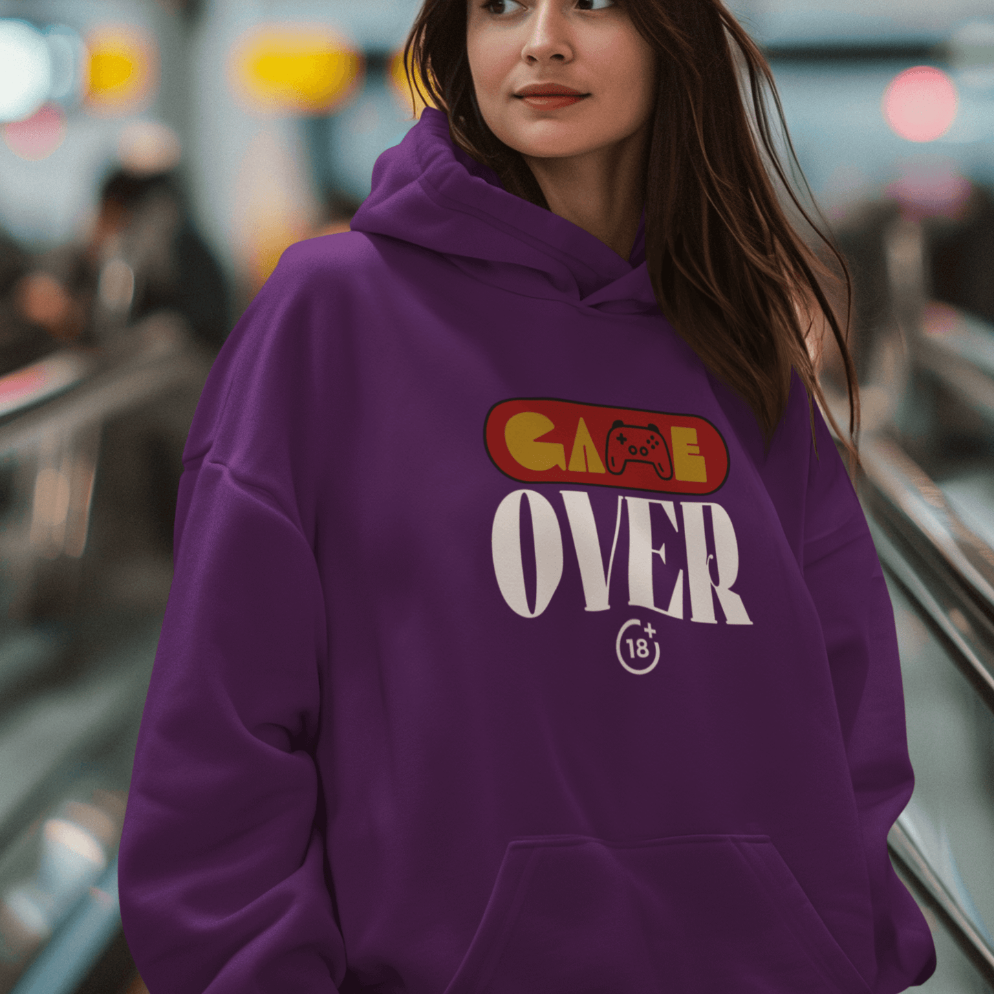 Female Model wearing purple hoodie with retro “Game Over” controller-themed graphic, unisex gamer streetwear by LostLogicCo Canada