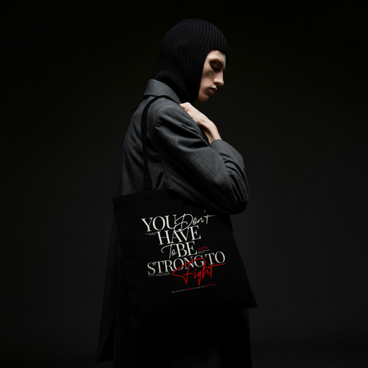 Eco tote bag with “You Don’t Have to Be Strong to Fight” motivational typography design in white and red on black organic cotton by LostLogicCo Canada.