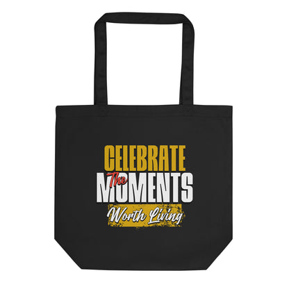 Eco tote bag with “Celebrate the Moments Worth Living” typography design in white, gold, and yellow on black organic cotton by LostLogicCo Canada.
