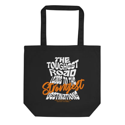 Eco tote bag with “The Toughest Road Leads to the Strongest Destinations” motivational typography design in white and orange on black organic cotton by LostLogicCo Canada.